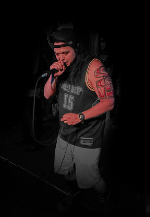 An image of Terracons member 2essentialz wearing a hat, on stage with microphone in hand.