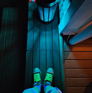 An Image looking down at the floor, showing Shoes with Green Laces.